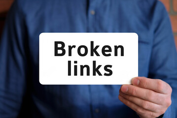 Broken links text on a white sign in the hand of a man in a blue shirt