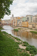 Girona's skyline on a cloudy day with water reflection river houses, bridge and massive cathedral on the horizon