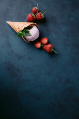 Strawberry ice cream scoop in waffle cone. Delicious refreshing seasonal sweets for summer