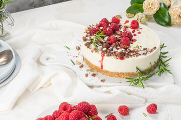 Cheesecake with raspberries, chocolate, hazelnuts and rosemary leaves on kitchen coutertop