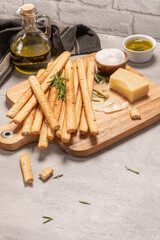 Traditional italian breadsticks grissini with rosemary, parmesan cheese, olive oil, garlic and salt on a gray background.