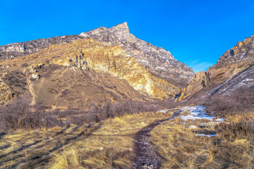 Trail on a grassy terrain with view of a rocky mountain in Provo Canyon Utah
