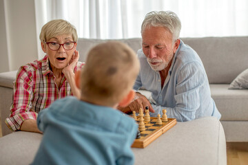 Grandparents playing chess with their grandson at home