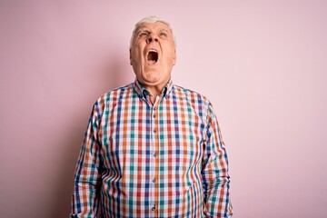 Senior handsome hoary man wearing casual colorful shirt over isolated pink background angry and mad screaming frustrated and furious, shouting with anger. Rage and aggressive concept.