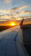 View through the plane window to the right wing of the plane and the sunset