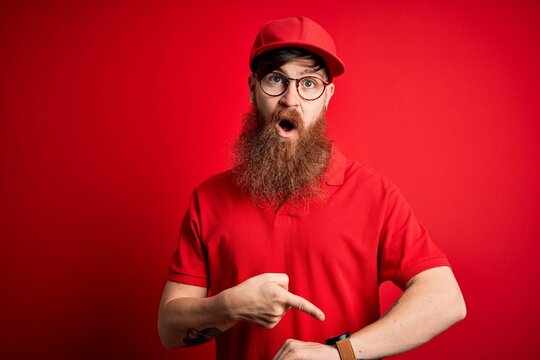 Young Handsome Delivery Man Wearing Glasses And Red Cap Over Isolated Background In Hurry Pointing To Watch Time, Impatience, Upset And Angry For Deadline Delay