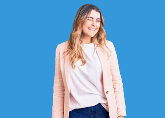 Young caucasian woman wearing business clothes winking looking at the camera with sexy expression,...
