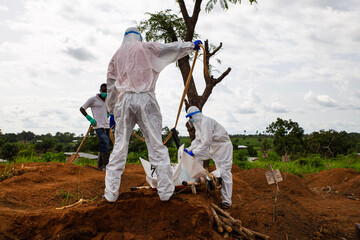 Lunsar, Sierra Leone - June 24, 2015: members of the burial team bury an ebola dead person in the...