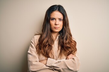Young beautiful brunette woman wearing casual shirt standing over white background skeptic and nervous, disapproving expression on face with crossed arms. Negative person.