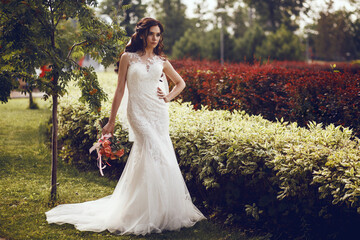 Fashion portrait of a beautiful bride. The bride in a white wedding dress stands against the...