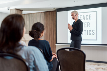 World of Opportunities. Female speaker in suit with headset giving a talk on Peace over Politics on corporate business meeting