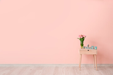 Table with flowers near color wall in room