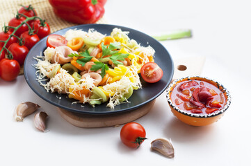 Colorful pasta with cheese, tomatoes, garlic, parsley, pepper on a black plate. Pasta for child with tomato sauce on a white background