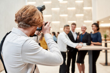 A moment to remember. Close up of photographer taking photo of businesspeople during coffee break...