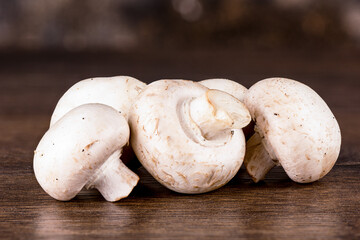Unpeeled fresh champignon mushrooms on a wooden table.
