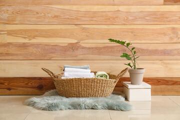 Basket with laundry near wooden wall