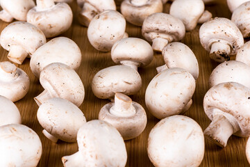 Fresh champignon mushrooms on a wooden background.