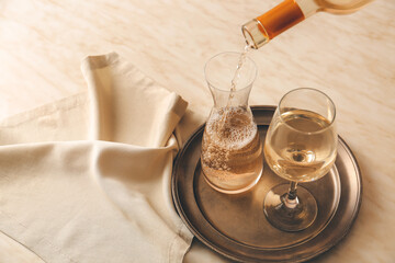 Pouring of wine from bottle into decanter on table