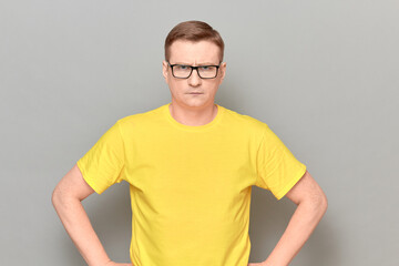 Portrait of serious mature man with glasses, wearing yellow T-shirt
