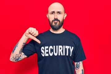 Young handsome man wearing security t shirt with angry face, negative sign showing dislike with...