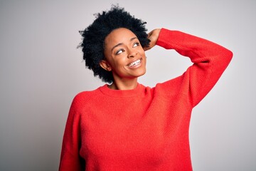 Fototapeta na wymiar Young beautiful African American afro woman with curly hair wearing red casual sweater smiling confident touching hair with hand up gesture, posing attractive and fashionable