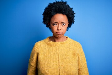 Fototapeta na wymiar Young beautiful African American afro woman with curly hair wearing yellow casual sweater depressed and worry for distress, crying angry and afraid. Sad expression.