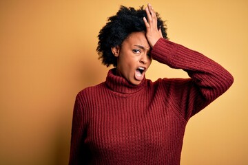 Fototapeta na wymiar Young beautiful African American afro woman with curly hair wearing casual turtleneck sweater surprised with hand on head for mistake, remember error. Forgot, bad memory concept.