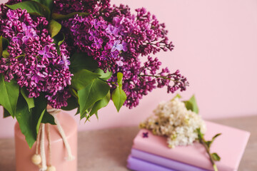Vase with beautiful flowers and books on table, closeup