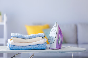 Stack of clean clothes on ironing board in room