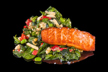 Delicious fresh salad with spinach, salmon, and edamame with reflection, isolated on black background