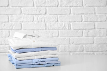 Stack of clean clothes on table against white brick background