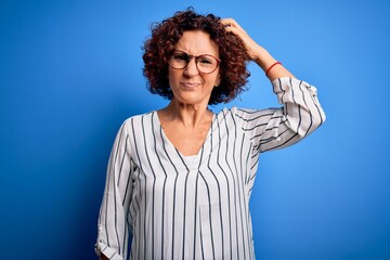 Middle age beautiful curly hair woman wearing casual striped shirt over isolated background confuse...