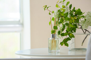 Reed diffuser and flowers on table in room