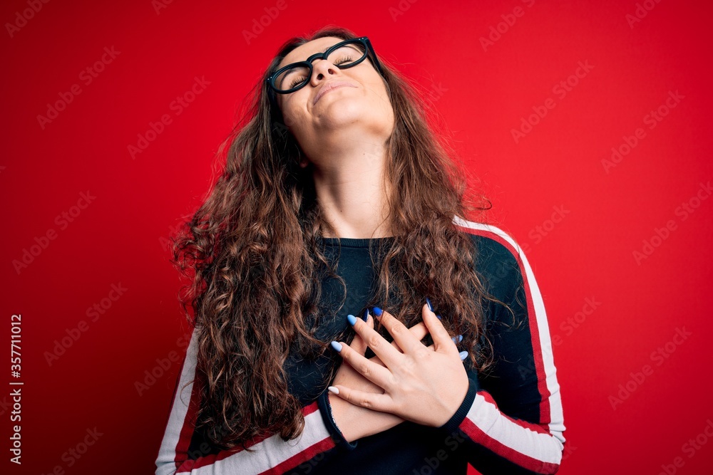 Sticker young beautiful woman with curly hair wearing sweater and glasses over red background smiling with h