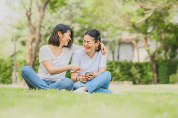 Asian women laughing while using smartphone outdoor
