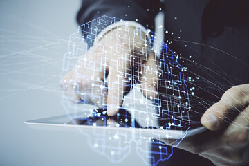 Double exposure of man's hand holding and using a digital device and brain hologram drawing. Data...