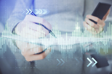 Double exposure of forex chart sketch hologram and woman holding and using a mobile device. Financial market concept.