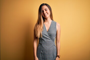 Young beautiful blonde woman with blue eyes wearing dress over yellow background with a happy and cool smile on face. Lucky person.