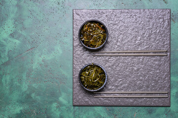 Bowls with tasty seaweed and chopsticks on table
