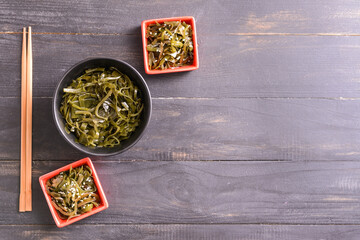 Bowls with tasty seaweed and chopsticks on table