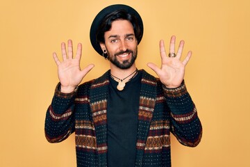 Young handsome hispanic bohemian man wearing hippie style and boho hat showing and pointing up with...