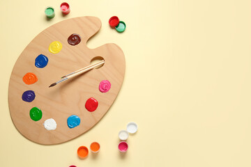 Artist's palette, brushes and paints on color background
