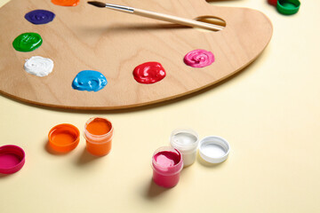 Artist's palette, brush and paints on color background