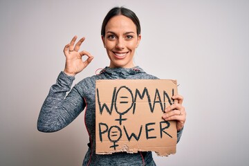 Young fitness woman wearing sport clothes holding protest cardboard for women power doing ok sign with fingers, excellent symbol