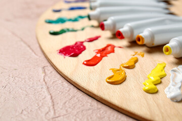 Paints and artist's palette on color background, closeup