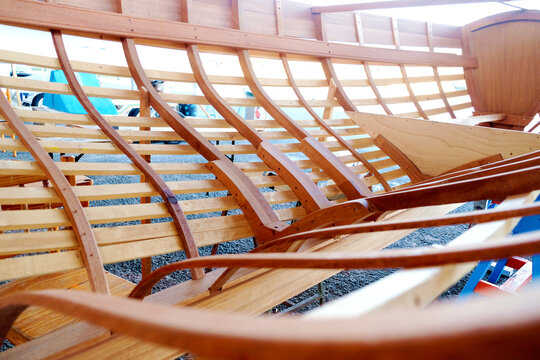 Small boatyard construction of a wooden boat. Ribs, keel, bulkheads and longitudinal members visible.