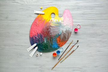Paints, brushes and artist's palette on wooden background