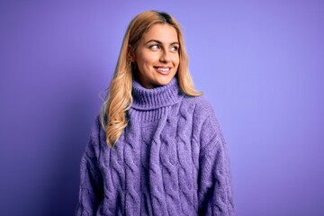 Fototapeta premium Young beautiful blonde woman wearing casual turtleneck sweater over purple background looking away to side with smile on face, natural expression. Laughing confident.
