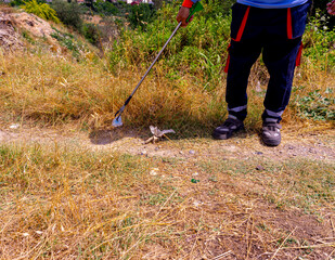 Closeup of hand and waste grabber picking up drinking plastic bottle waste into bag. Ecology and...