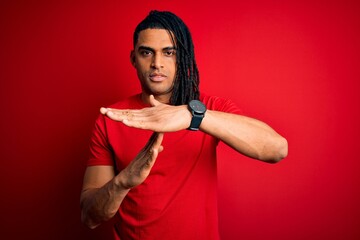 Young handsome african american afro man with dreadlocks wearing red casual t-shirt Doing time out gesture with hands, frustrated and serious face